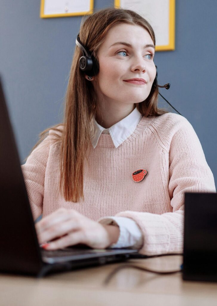 Friendly customer support woman working in an office, using a computer.